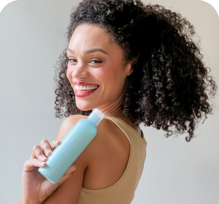 Beautiful biracial woman with curly hair holding van + veronica Haircare Leave-In