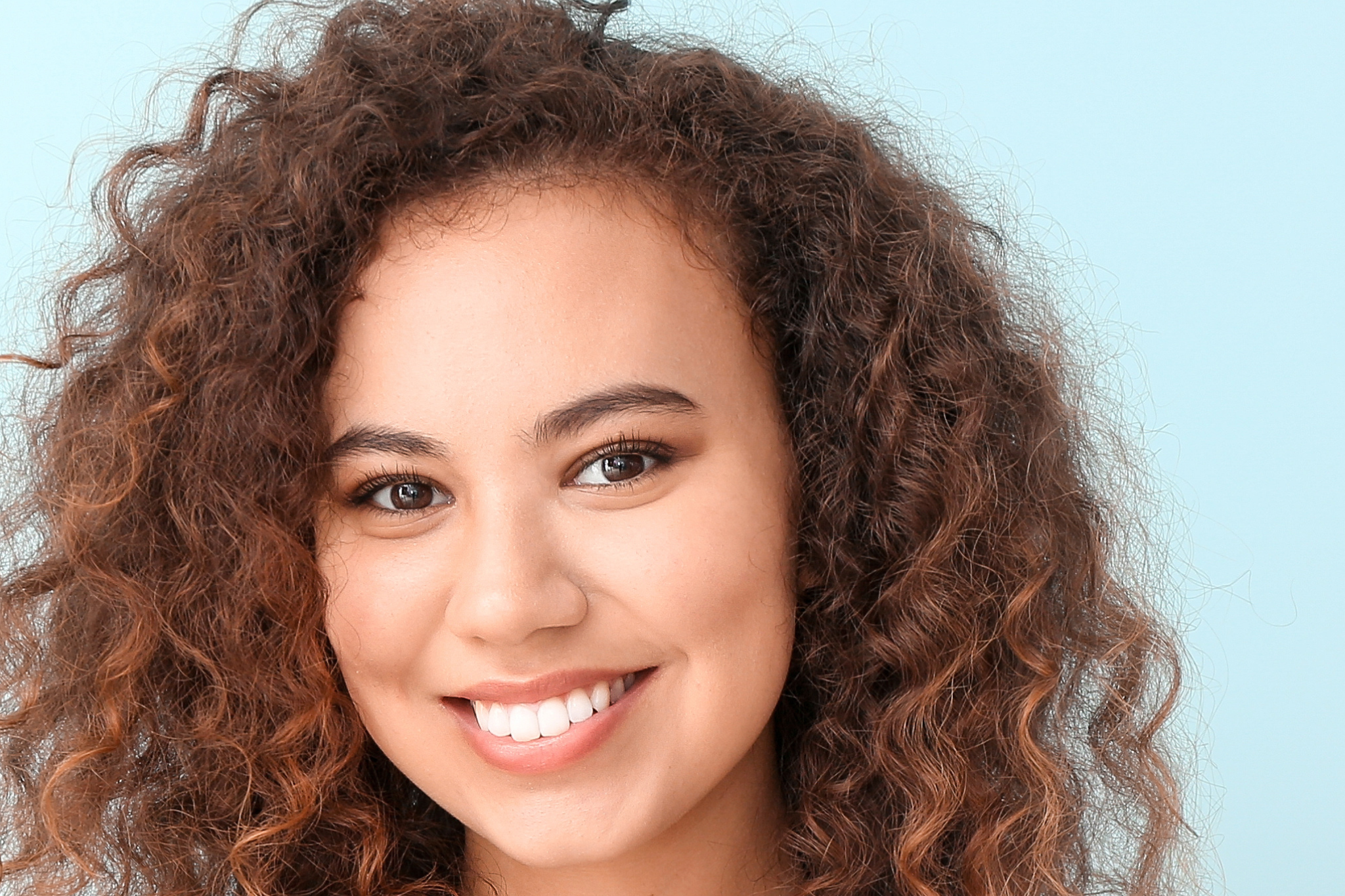 Pretty woman, blue background, with fine, thin curly hair, smiling