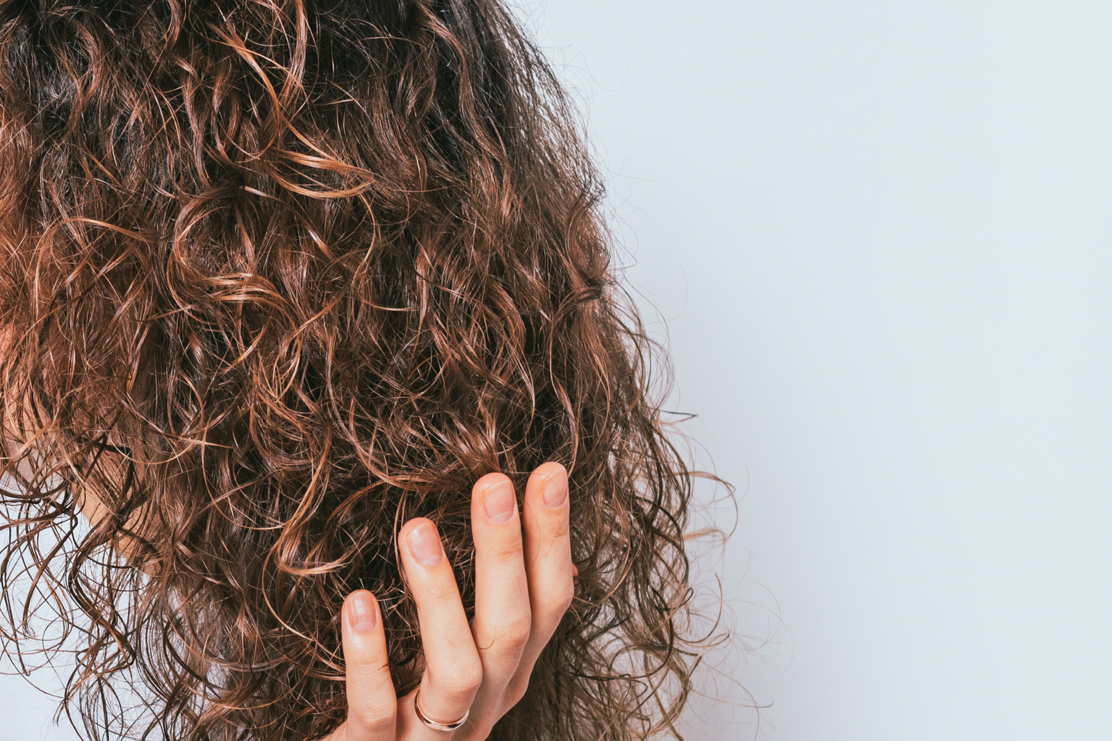 Woman with fine curly hair touching her curls