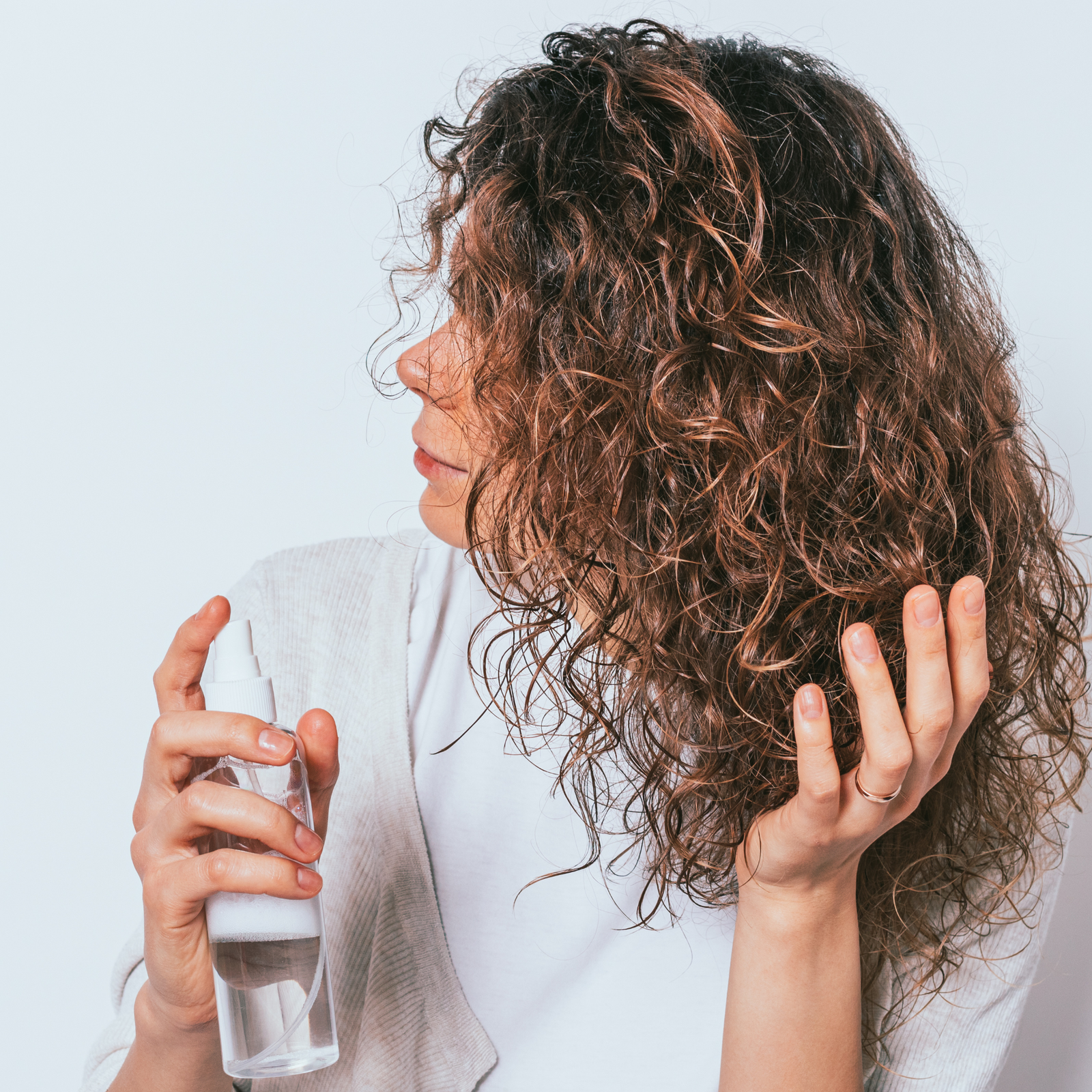 Woman with fine curly hair holding spray bottle