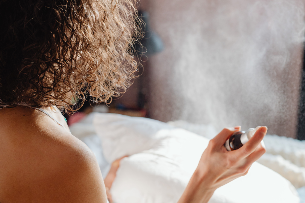 Woman with fine curly hair, spray perfumed product