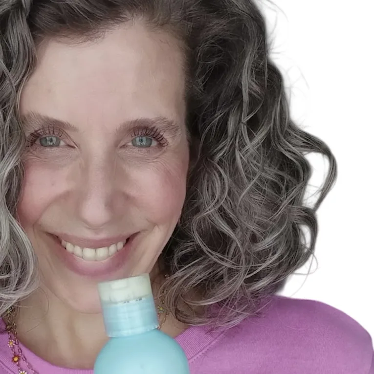 Beautiful woman with gray curly hair, showing results after using The Haven Collection by van + veronica Haircare